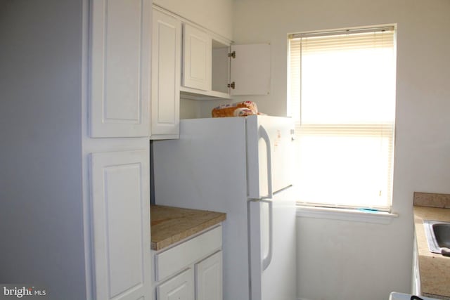 kitchen with white cabinets, white fridge, and a healthy amount of sunlight