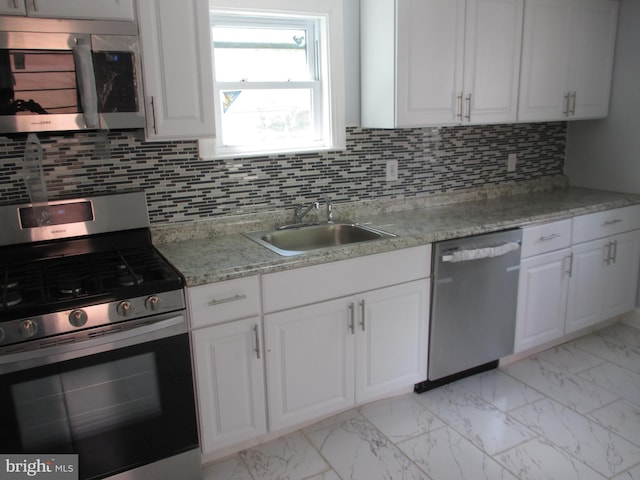 kitchen with decorative backsplash, light stone countertops, white cabinetry, and appliances with stainless steel finishes