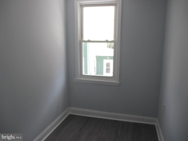 empty room featuring a wealth of natural light and dark wood-type flooring