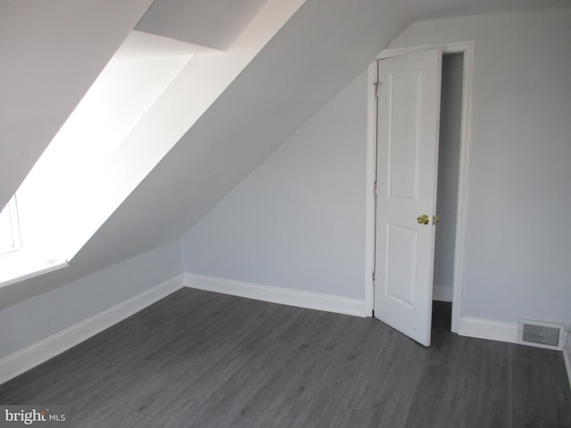 bonus room with lofted ceiling with skylight and dark wood-type flooring