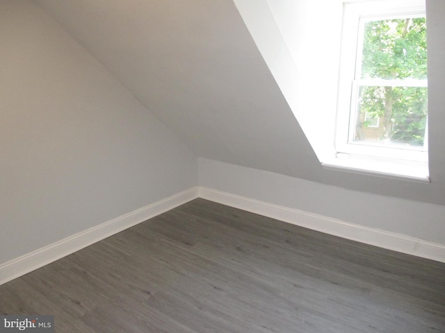 bonus room with dark wood-type flooring and vaulted ceiling