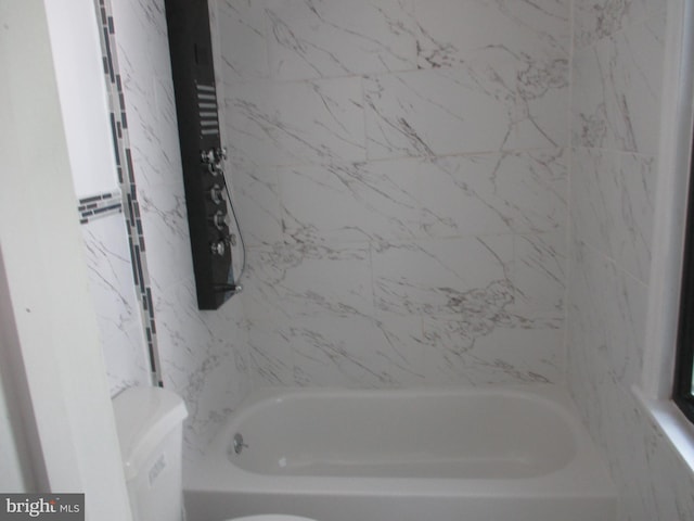 bathroom with tiled shower / bath combo and toilet