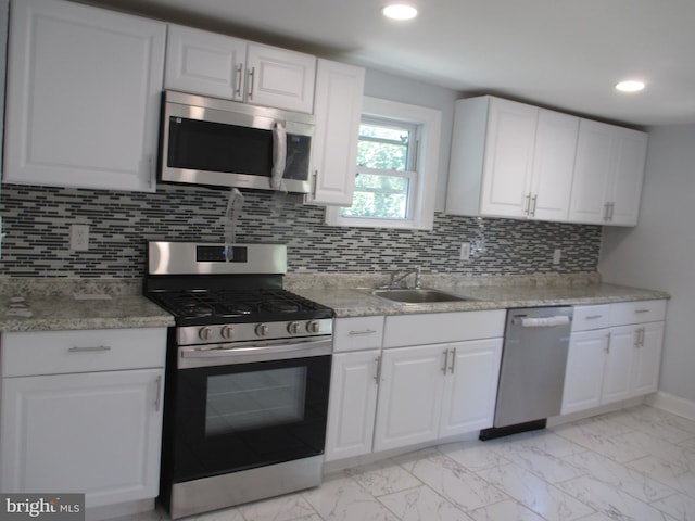 kitchen with tasteful backsplash, white cabinets, and stainless steel appliances