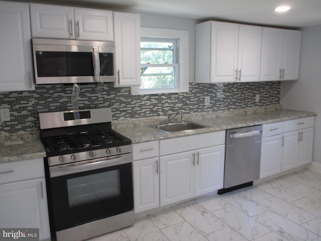 kitchen featuring white cabinets, decorative backsplash, stainless steel appliances, and sink