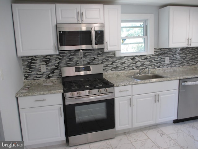 kitchen featuring white cabinetry, sink, light stone counters, decorative backsplash, and appliances with stainless steel finishes