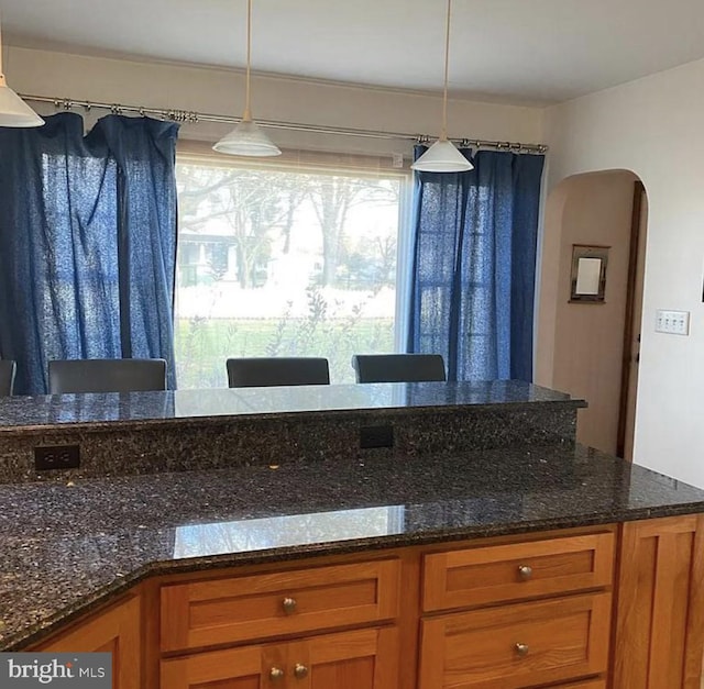 kitchen featuring dark stone counters and hanging light fixtures