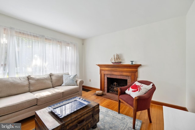 living room with wood-type flooring and a brick fireplace