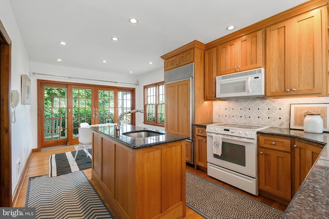 kitchen with french doors, white appliances, sink, and light hardwood / wood-style flooring