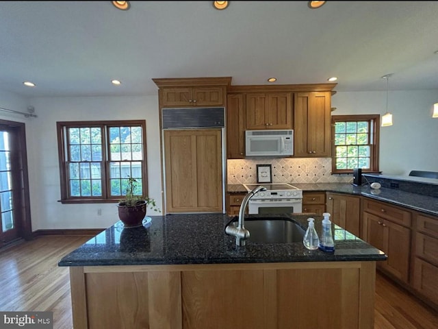 kitchen with white appliances, light hardwood / wood-style floors, and dark stone countertops