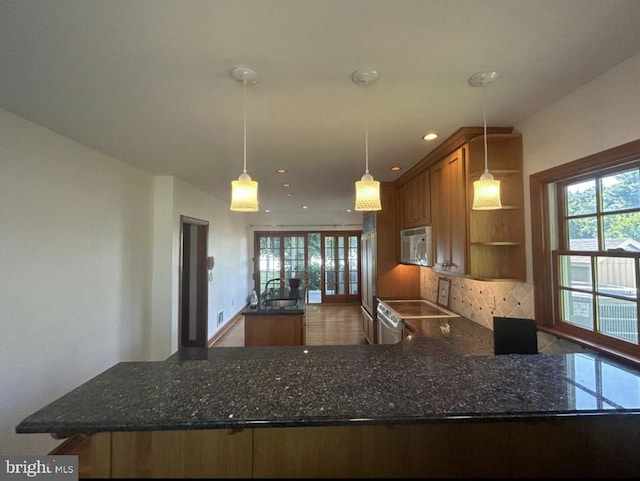 kitchen with kitchen peninsula, decorative light fixtures, dark stone countertops, and electric stove