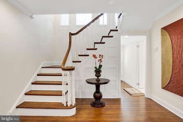 stairs with wood-type flooring and crown molding