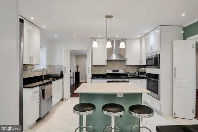 kitchen with white cabinets, wall chimney exhaust hood, stainless steel appliances, and hanging light fixtures