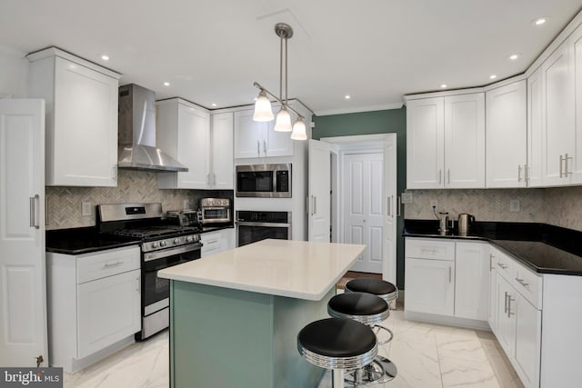 kitchen featuring white cabinets, pendant lighting, wall chimney exhaust hood, and stainless steel appliances