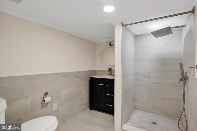 bathroom featuring tiled shower, vanity, tile walls, and crown molding