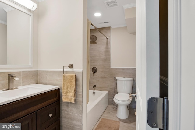 full bathroom featuring vanity, toilet, tile walls, and tiled shower / bath combo