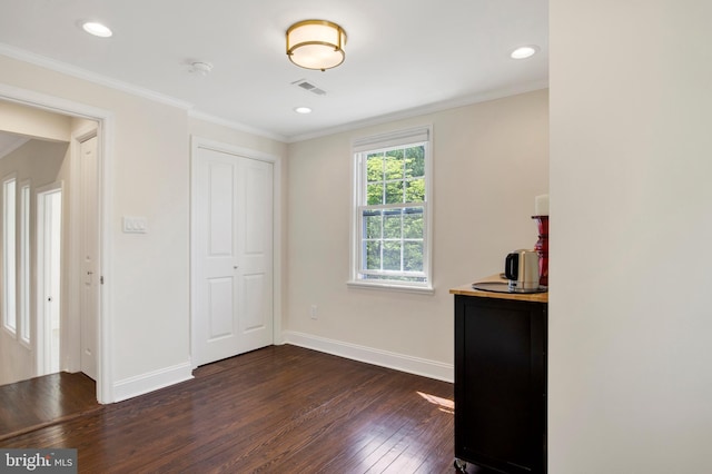 unfurnished bedroom featuring ornamental molding, a closet, and dark wood-type flooring