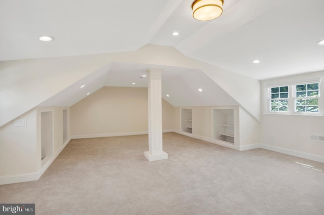 additional living space featuring built in features, light carpet, and vaulted ceiling