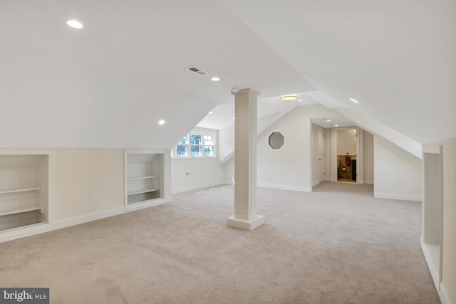 additional living space with built in shelves, light colored carpet, and vaulted ceiling