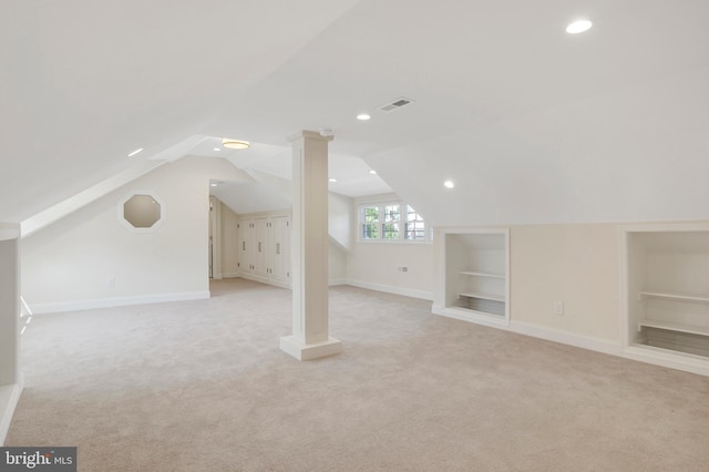 additional living space featuring built in features, light carpet, and vaulted ceiling