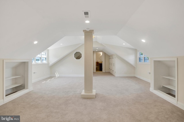 additional living space featuring built in features, light carpet, and vaulted ceiling