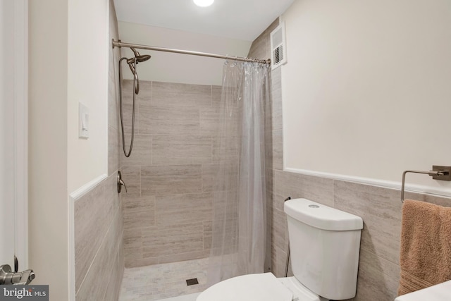 bathroom with walk in shower, toilet, and tile walls