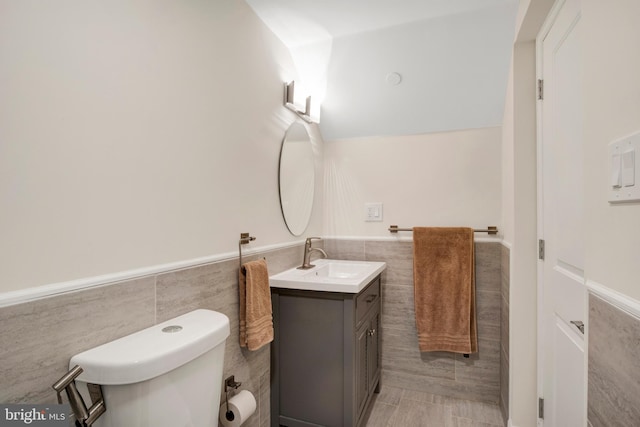 bathroom with tile patterned floors, vanity, toilet, and tile walls