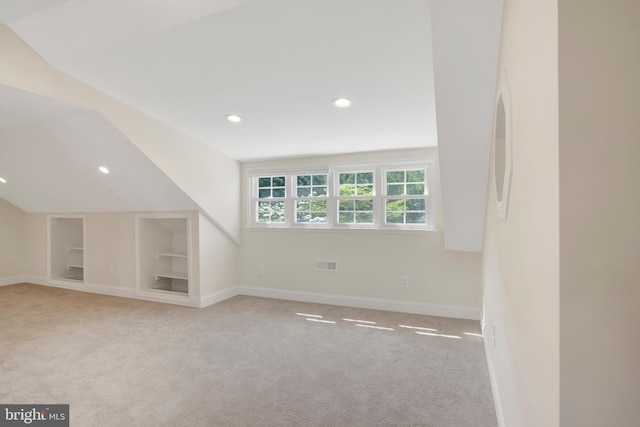 additional living space with light carpet, built in features, and lofted ceiling