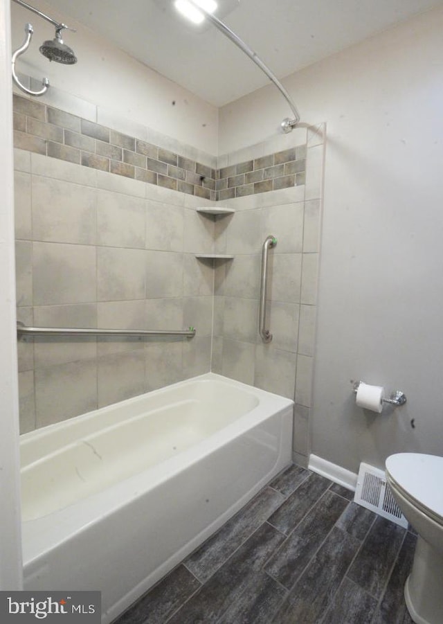 bathroom with toilet and tiled shower / bath