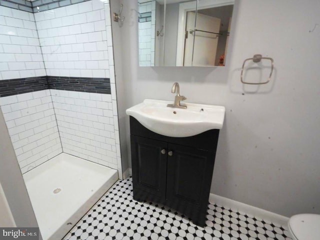 bathroom with vanity, toilet, and a tile shower