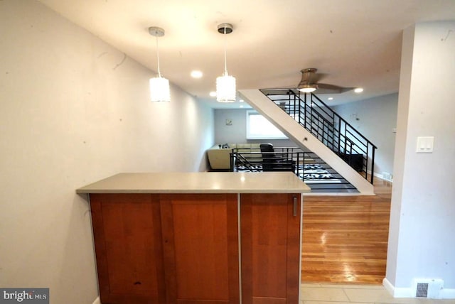 kitchen featuring kitchen peninsula, light wood-type flooring, decorative light fixtures, and ceiling fan