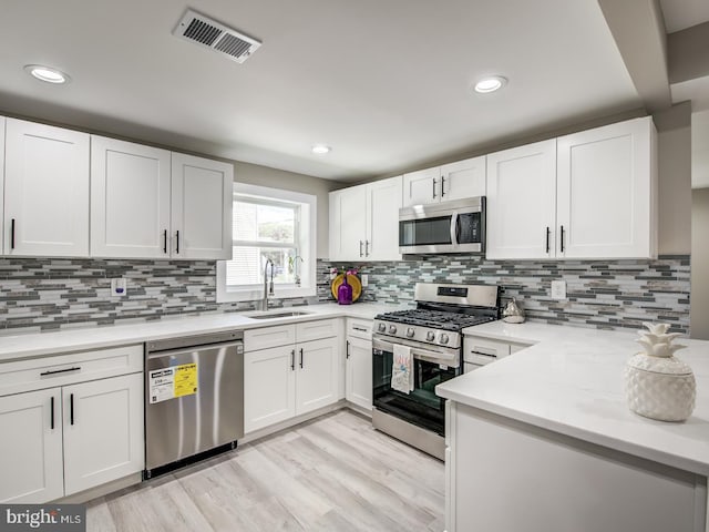 kitchen with white cabinets, decorative backsplash, sink, and stainless steel appliances