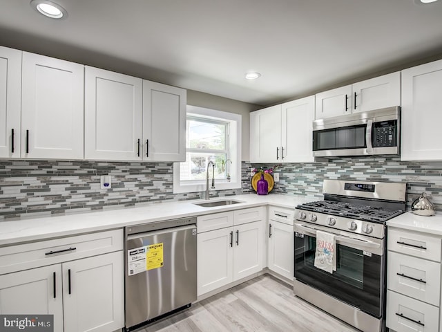 kitchen with stainless steel appliances, decorative backsplash, white cabinets, and sink