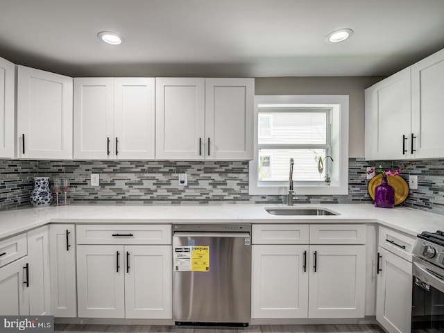 kitchen featuring white cabinets, decorative backsplash, appliances with stainless steel finishes, and sink