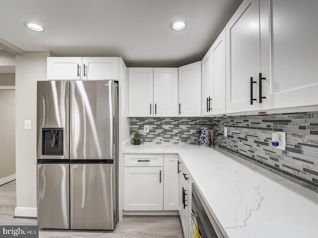 kitchen featuring white cabinets, stainless steel fridge, and light stone countertops