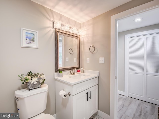 bathroom with toilet, hardwood / wood-style floors, and vanity