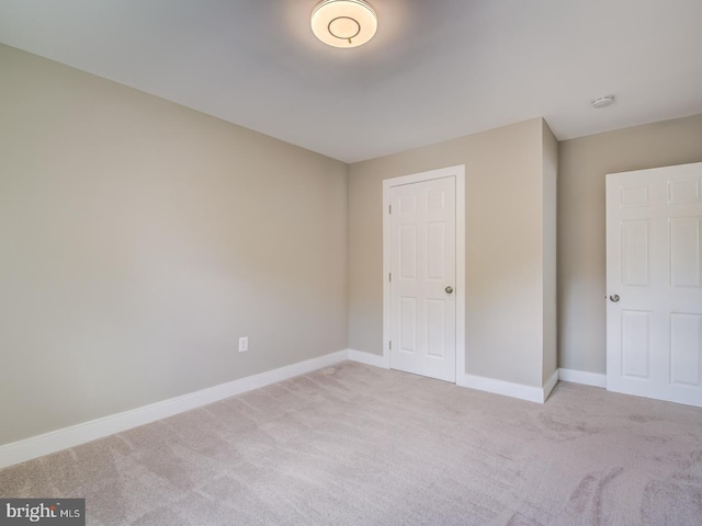 unfurnished bedroom with light colored carpet and a closet