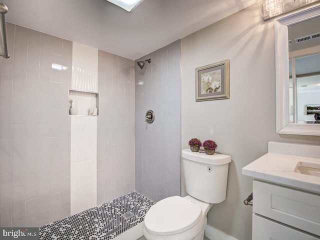 bathroom featuring toilet, a tile shower, and vanity