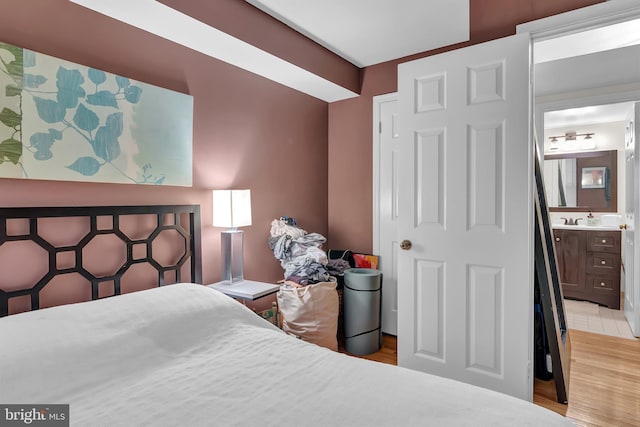 bedroom featuring ensuite bathroom, light hardwood / wood-style flooring, and sink