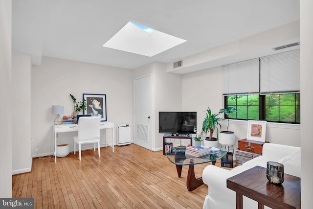 living room with a skylight and light hardwood / wood-style floors