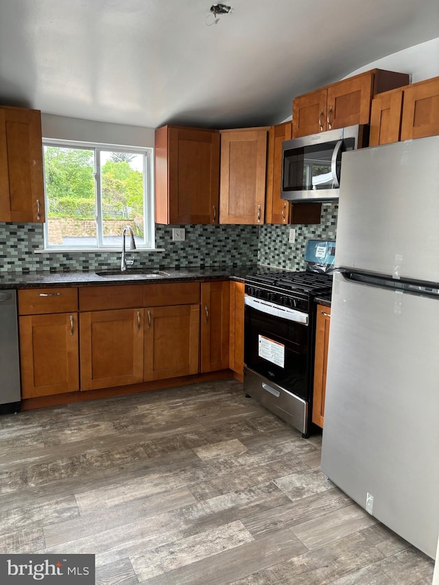 kitchen with hardwood / wood-style floors, sink, stainless steel appliances, and tasteful backsplash