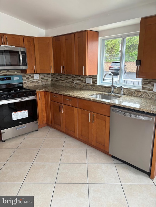 kitchen featuring backsplash, sink, vaulted ceiling, dark stone countertops, and stainless steel appliances