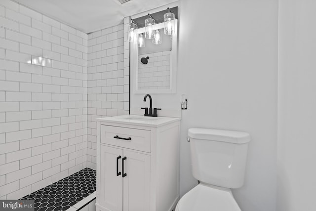 bathroom with a tile shower, vanity, and toilet