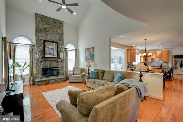 living room with a wealth of natural light, light wood-type flooring, and a stone fireplace