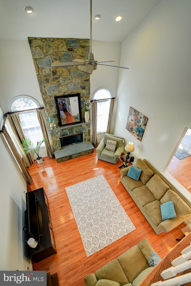 living room with recessed lighting, a high ceiling, wood finished floors, and a fireplace