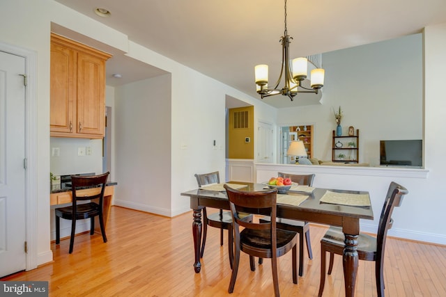 dining space featuring a chandelier, light wood-style flooring, and baseboards