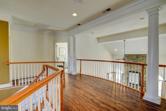 hall featuring visible vents, an upstairs landing, wood finished floors, crown molding, and decorative columns