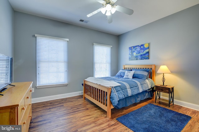 bedroom with visible vents, a ceiling fan, baseboards, and wood finished floors