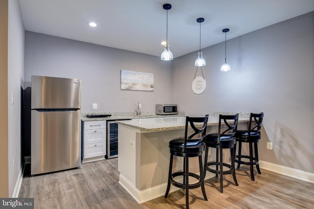 kitchen with a breakfast bar, wine cooler, light wood finished floors, and stainless steel appliances