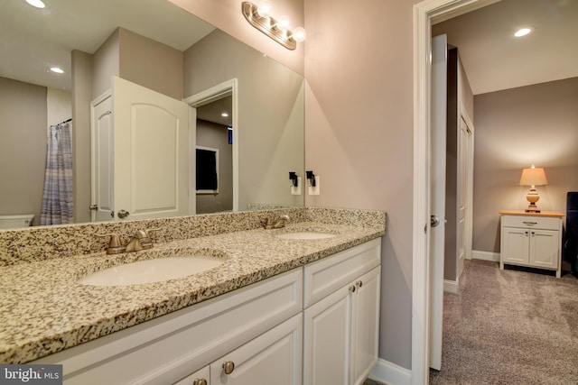 full bath featuring double vanity, recessed lighting, baseboards, and a sink