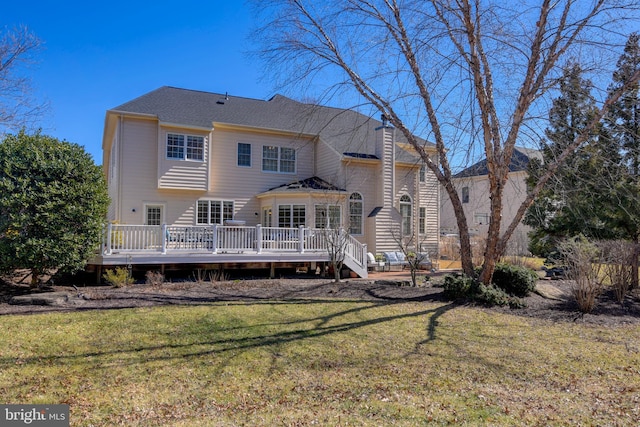 rear view of property featuring a deck, a lawn, and a chimney